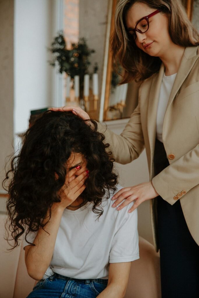 A young woman receiving comforting support during an emotional therapy session indoors.